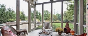 Picture of the interior of a sunroom with a backyard in the background.